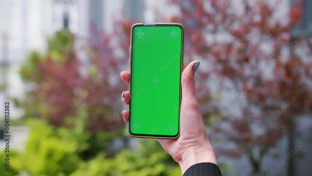 Close up hands woman holding phone with vertical green screen on street ...