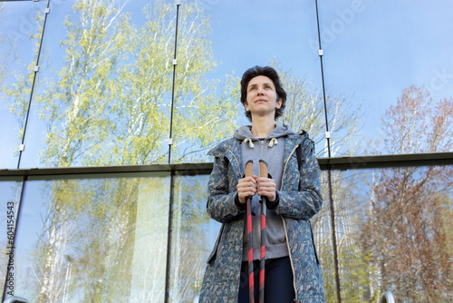 Pole Walking Girl In Urban Area, City Beautiful Happy Caucasian Woman Training With Sticks Outdoor, Modern Glass Eco Building on Background. Physical Activity, Nordic Walk, Recreation. Horizontal