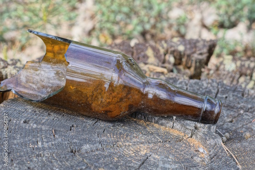Canvas Print one brown broken glass bottle lies on a gray wooden stump on the street