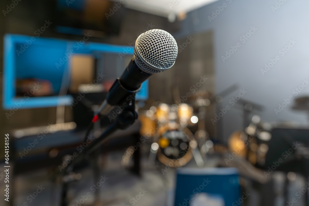 Microphone in a recording studio with a blurred background including a drum kit.
Microphone in a recording studio with a blurred background including a drum kit.