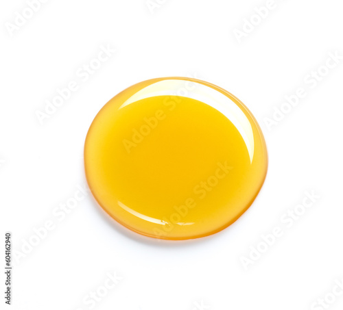 Beautiful drop of honey or other yellow liquid isolated on white background. Yellow or orange drop of oil on a light background
