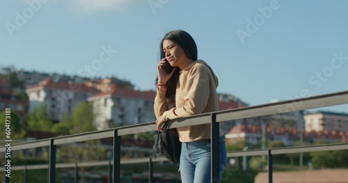 Young teenage latin college student using social networks with her smartphone in a park