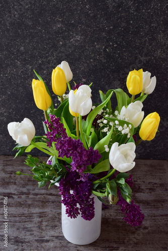 A beautiful bouquet of tulips and lilacs in a white vase, top view