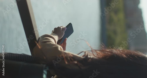 Young teenage Latina college student using social networks with her smartphone in a park, vertical shot