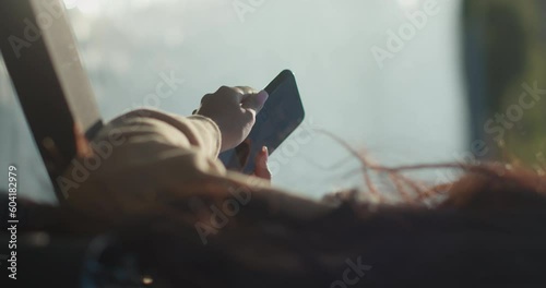 Young teenage Latina college student using social networks with her smartphone in a park, vertical shot