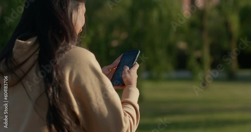Young teenage latin college student using social networks with her smartphone in a park