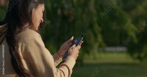 Young teenage latin college student using social networks with her smartphone in a park