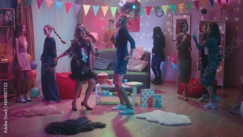 A company of teenagers dance incendiary at a house party, except for one informal girl. The interior of the room is decorated with a disco ball, flags and balloons for the party.