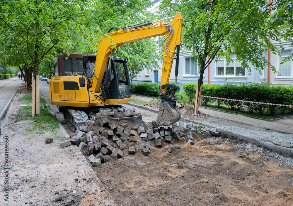 Excavator during the cobblestone street reconstruction. Loading old cobblestone. Excavator during the cobblestone street reconstruction. Loading old cobblestone.