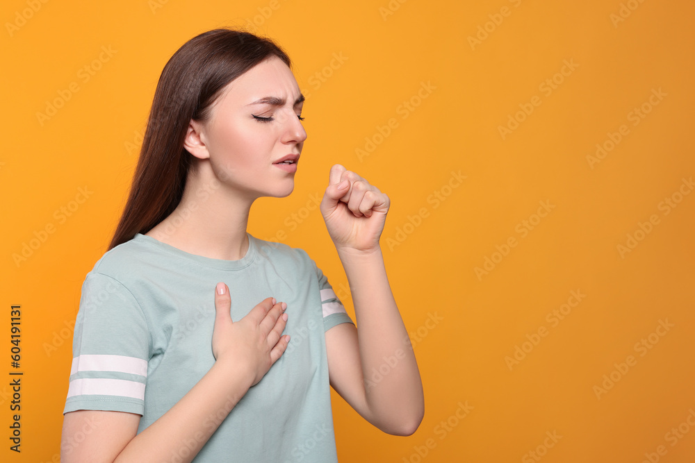 Young woman coughing on orange background, space for text. Sore throat Young woman coughing on orange background, space for text. Sore throat