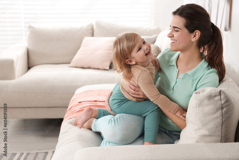 Mother with her cute little daughter on sofa at home, space for text Mother with her cute little daughter on sofa at home, space for text
