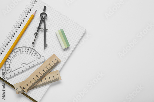 Different rulers, compass, pencil and notebook on white background, top view. Space for text