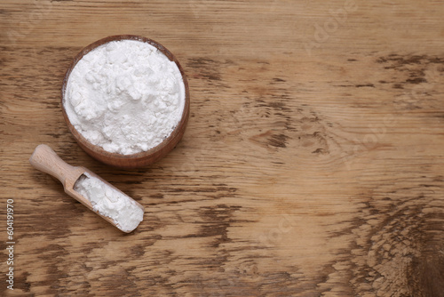 Bowl and scoop of natural starch on wooden table, flat lay. Space for text photo