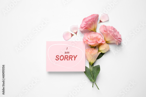 Apology. Pink card with circled phrase I Am Sorry and beautiful Eustoma flowers on white background, flat lay. Space for text