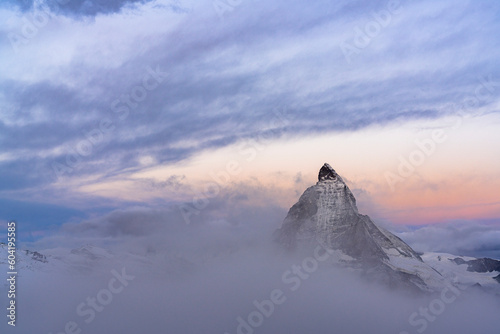 Clouds over Matterhorn peak emerging from mist at sunrise, Gornergrat, Zermatt, canton of Valais, Switzerland photo
