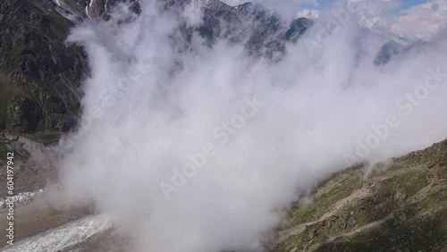 Aerial: Cloudy mountain gorge with glacier at sunny day photo