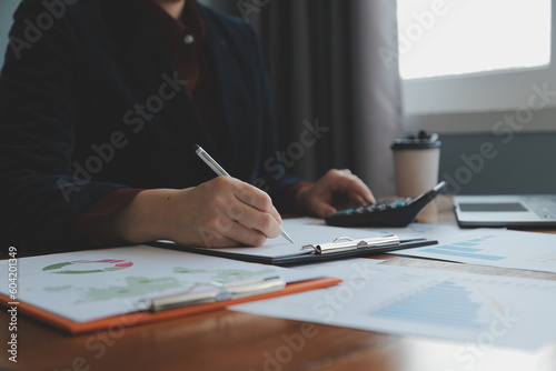 Group of confident business people point to graphs and charts to analyze market data, balance sheet, account, net profit to plan new sales strategies to increase production capacity.