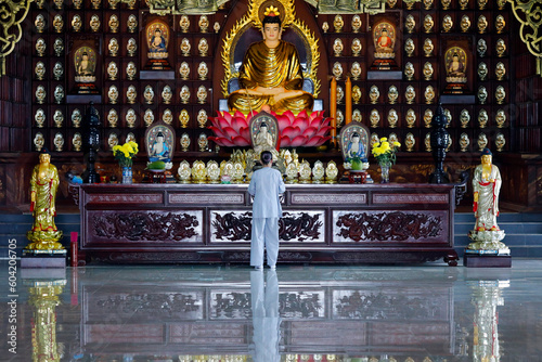 Woman praying at main altar, Phat Quang Buddhist temple, Siddhartha Gautama (the Shakyamuni Buddha), Chau Doc, Vietnam photo