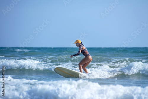 Asian surfing woman riding the waves on sunny day, outdoor activities, water sports activities concept © chomplearn_2001