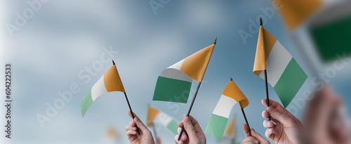 Fototapeta Naklejka Na Ścianę i Meble -  A group of people holding small flags of the Cote dIvoire in their hands