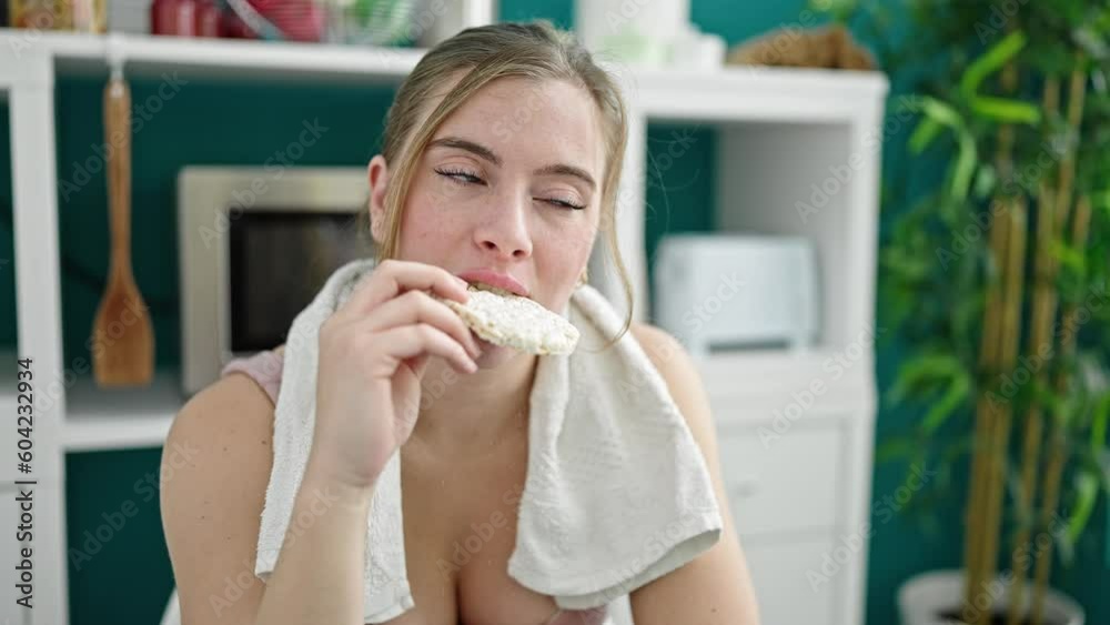 Young blonde woman wearing sportswear eating rice cake at dinning room Young blonde woman wearing sportswear eating rice cake at dinning room