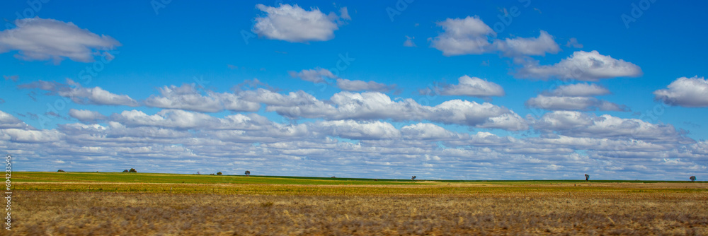 Farmland between Roma and Charleville with cloud formations. Blue sky with trees on hill top. Queensland, Australia.