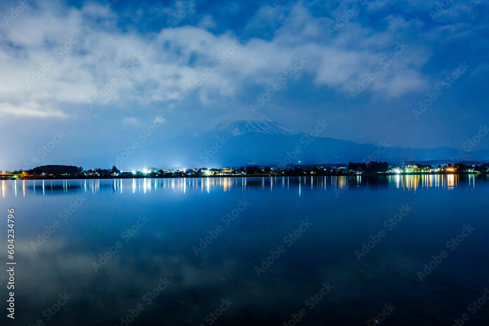 暗闇に浮かび上がる富士山と夜中の河口湖に映る夜景