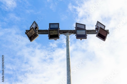 Spotlights on steel pole in stadium with blue sky background.