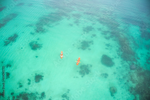 Aerial boat and people in ocean for kayak adventure, travel or journey at sea together in the outdoors. Couple traveling, kayaking or rowing on big calm, peaceful or serene beach water in nature