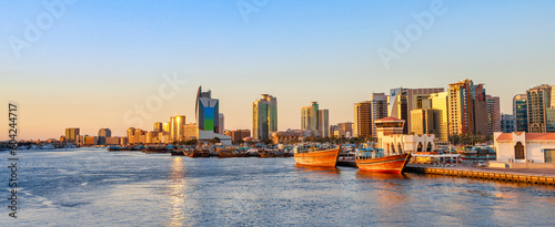 Photography Dubai Creek bay with skyscrapers, traditional boats and piers in UAE