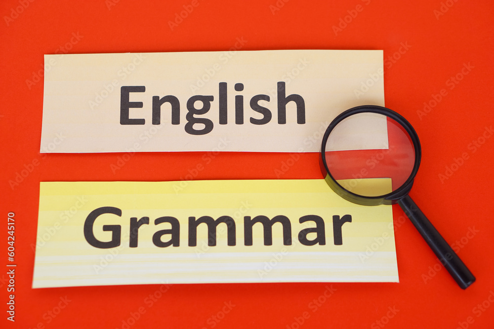 Word cards English Grammar, magnifying glass on red background. Concept, language learning. Find English grammar stucture. Education. School subjects. Word cards English Grammar, magnifying glass on red background. Concept, language learning. Find English grammar stucture. Education. School subjects.