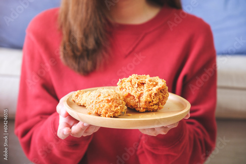 Closeup image of a young woman holding a plate of fried chicken