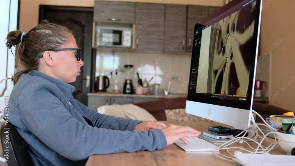 Woman with glasses typing on the keyboard with a focused expression. Work at home. Girl sits at her desktop with her computer. Camera filming side view move forward Woman with glasses typing on the keyboard with a focused expression. Work at home. Girl sits at her desktop with her computer. Camera filming side view move forward