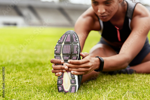 Woman, hands and stretching legs on grass at stadium in preparation for running, exercise or workout. Hand of active female person in warm up leg stretch, fitness or sports motivation on the field
