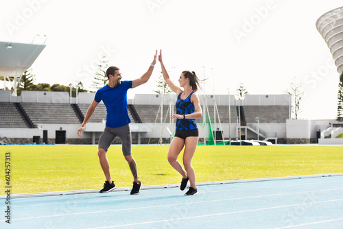 People, high five and running on stadium track for exercise, workout or training together in athletics. Man and woman touching hands in teamwork celebration for exercising, run or winning in fitness