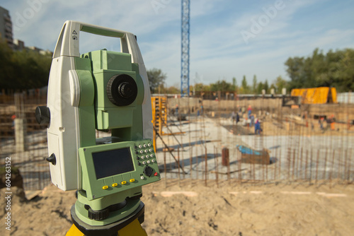 Close up view of technology equipment for measuring at construction site. Robotic total station with industrial background out of focus