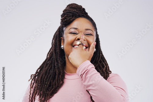 Portrait, funny face and finger on nose with a black woman in studio on a gray background looking silly or goofy. Comedy, comic and nostril with a crazy young female person joking for fun or humor photo