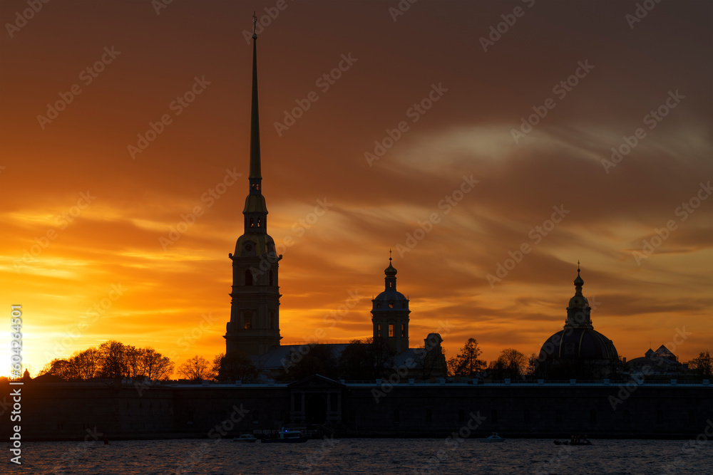 Peter and Paul Cathedral in the Peter and Paul Fortress against the background of a cloudy orange sunset. Saint Petersburg, Russia