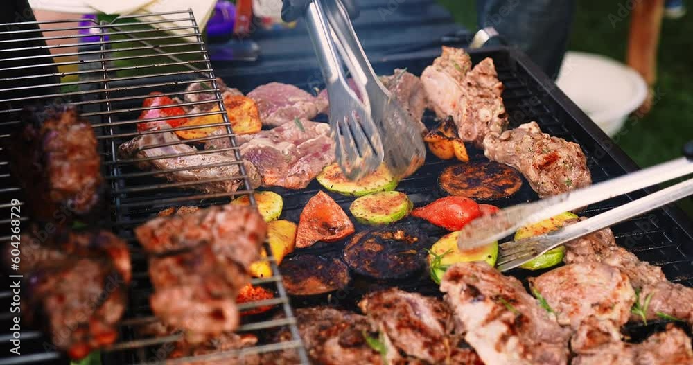 Chef grilling meat and vegetables on grill during summer barbeque party, close-up