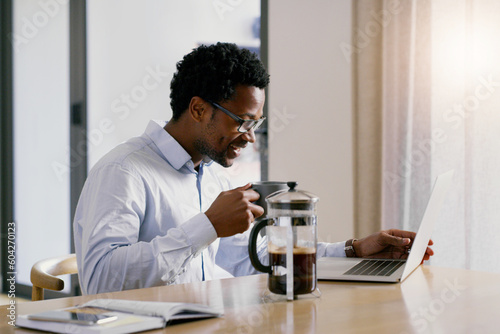Black man, coffee and laptop with a web call and meeting of freelancer worker at a table. Work from home, email and morning with a African male person on a computer for webinar and video conference