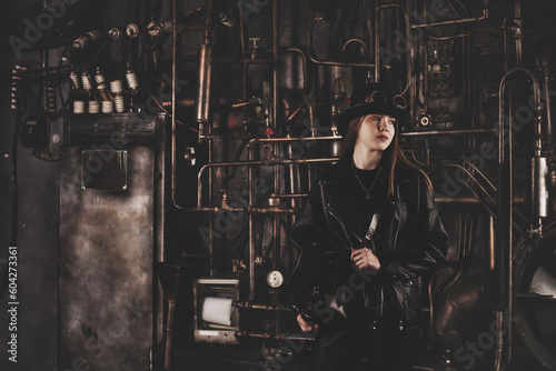 Classy teen girl model 12-13 year old in steampunk image in black leather jacket looking away. Toned image of teenage girl actress posing in industrial room. Adventure style concept. Copy text space