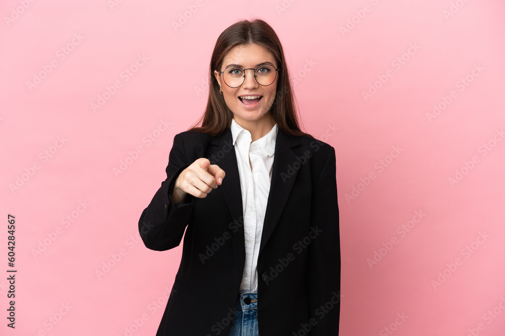Young Business caucasian woman isolated on pink background surprised and pointing front