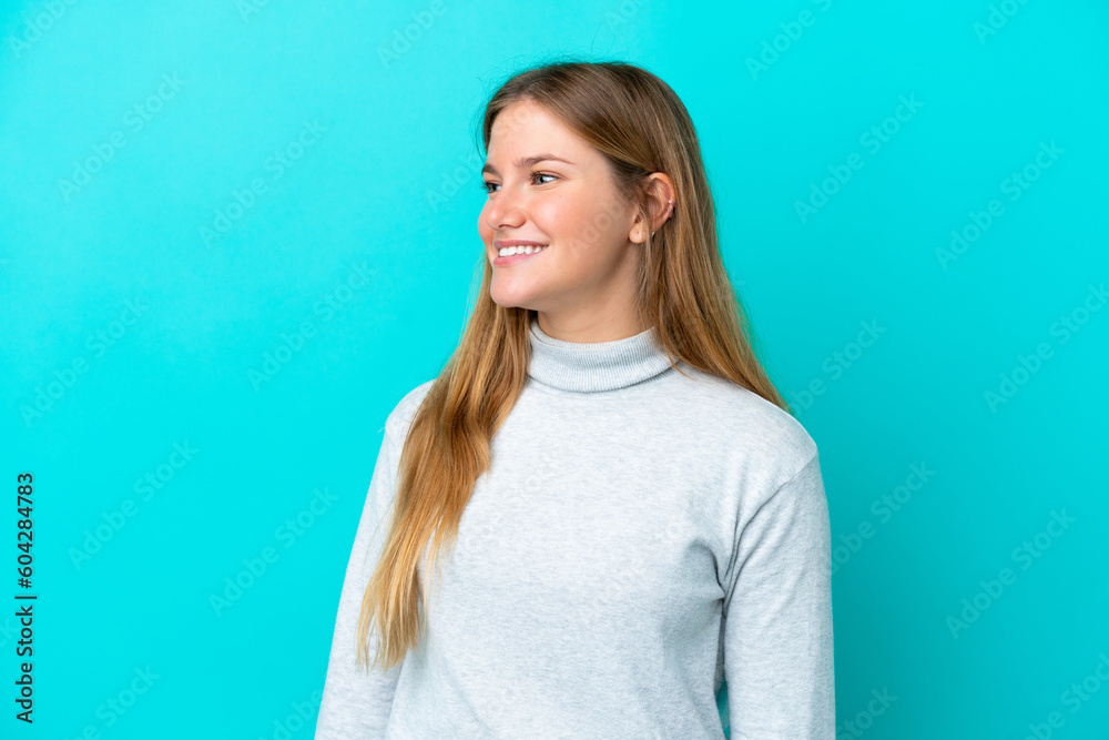 Young blonde woman isolated on blue background looking side Young blonde woman isolated on blue background looking side