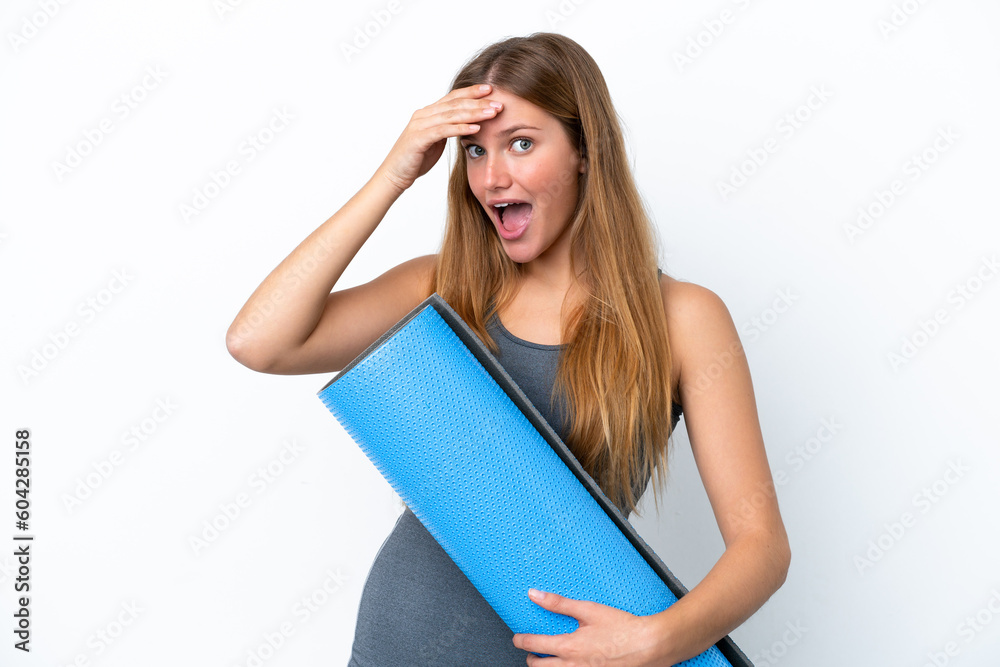 Young sport woman going to yoga classes while holding a mat doing surprise gesture while looking to the side Young sport woman going to yoga classes while holding a mat doing surprise gesture while looking to the side