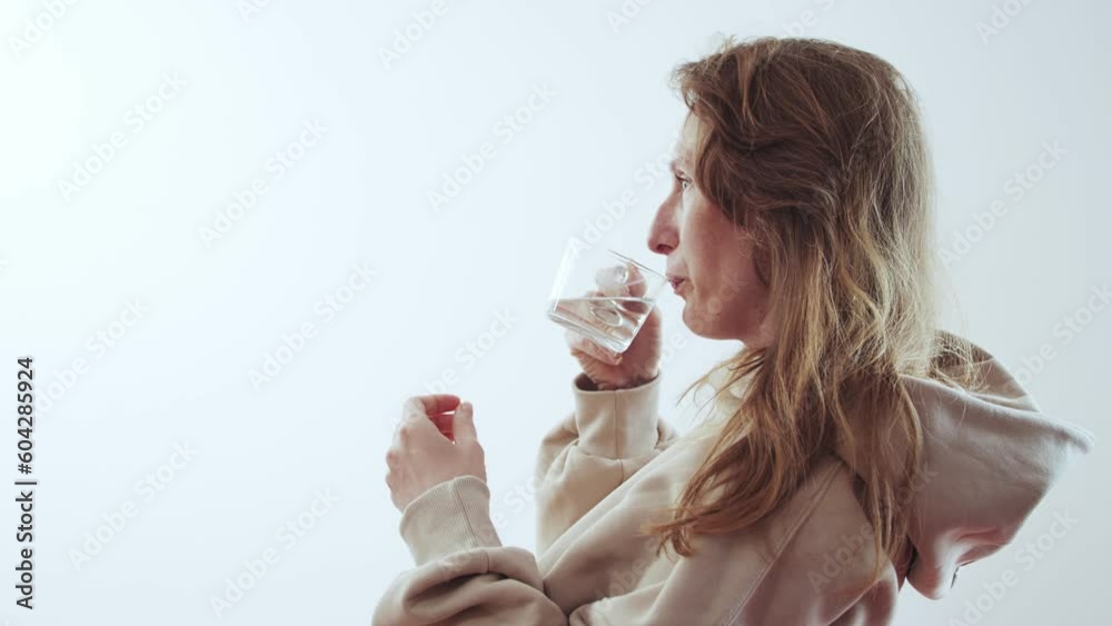 Young adult woman drinks water from a transparent cup Young adult woman drinks water from a transparent cup