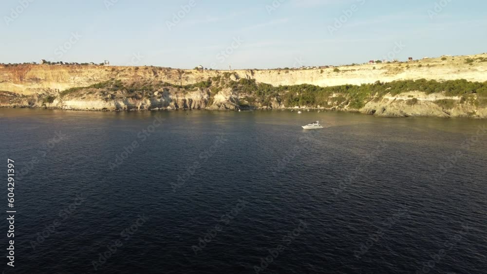 aerial view of a luxury sailing ship, with white sails, in the sea in the evening sunlight. luxurious summer adventure on a sailboat, offering an active vacation. aerial view of a luxury sailing ship, with white sails, in the sea in the evening sunlight. luxurious summer adventure on a sailboat, offering an active vacation.