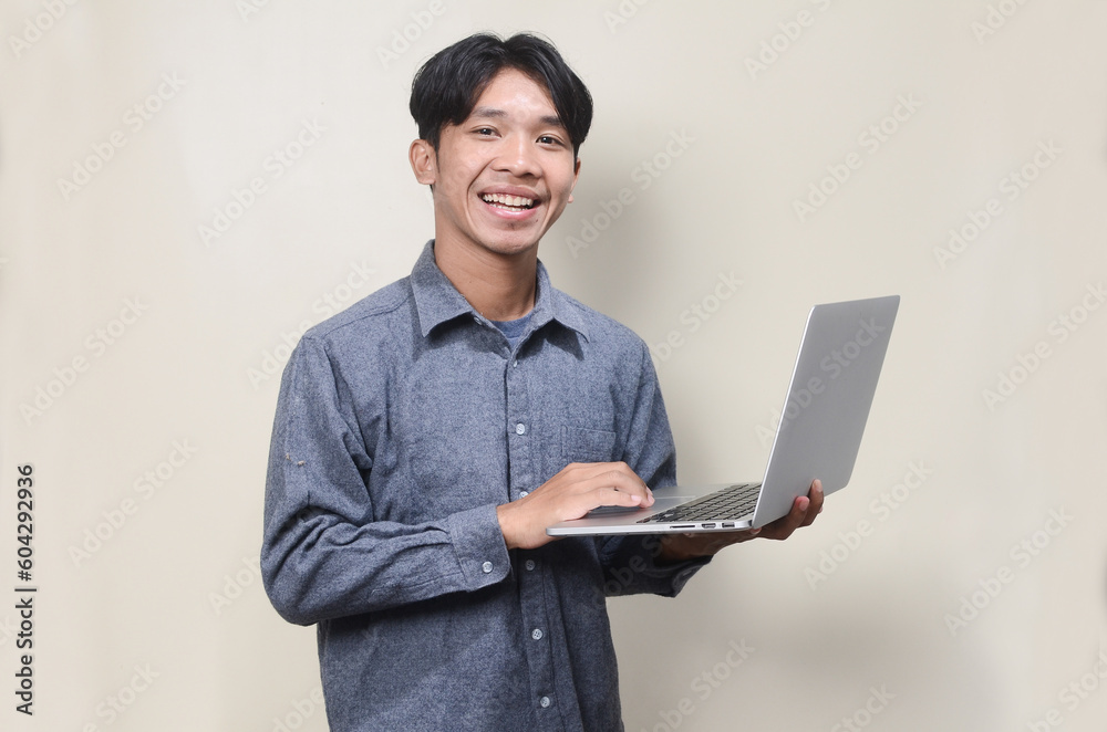 asian man wearing gray shirt holding laptop computer on isolated background asian man wearing gray shirt holding laptop computer on isolated background