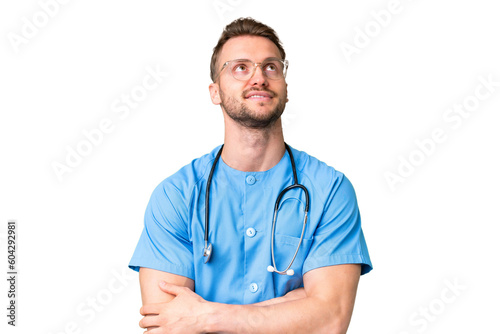 Young nurse man over isolated chroma key background looking up while smiling