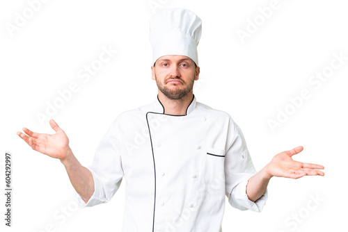 Young caucasian chef over isolated chroma key background having doubts while raising hands