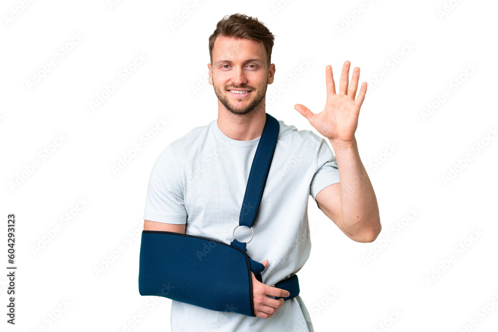 Young caucasian man with broken arm and wearing a sling over isolated chroma key background saluting with hand with happy expression Young caucasian man with broken arm and wearing a sling over isolated chroma key background saluting with hand with happy expression